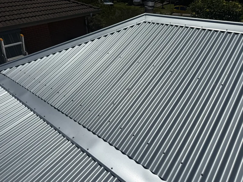 Unpainted corrugated metal roof with ridge capping by Auzsheet Roofing