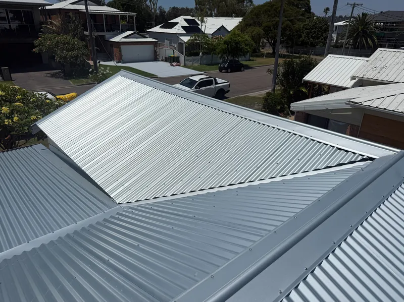 Unpainted corrugated metal roof meeting a lower roof section