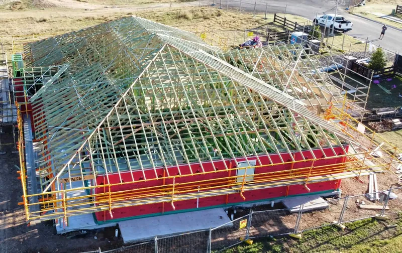 Roof framing above red-wrapped walls on the Tingira Heights job